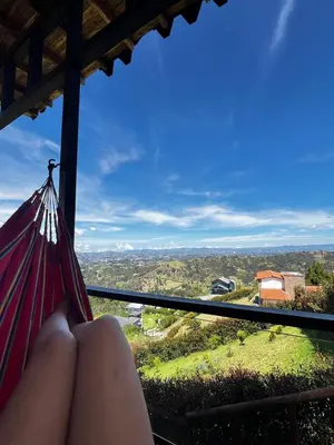a woman sitting in a hammock looking out of a window at Cabaña El Sueño de OPAD in Guarne
