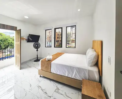 a bedroom with a bed and a tv and windows at Casa Eterna Campo Valdes in Medellín