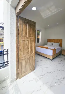 a bedroom with a bed and a large wooden door at Casa Eterna Campo Valdes in Medellín