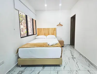 a bedroom with a bed in a white room at Casa Eterna Campo Valdes in Medellín