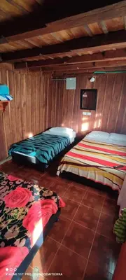 two beds in a room with wooden walls at Cabaña los Juanes, Jardin Antioquia in Jardin