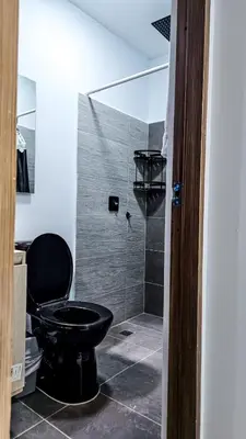 a bathroom with a black toilet and a shower at La Fonte di Luce in Santa Fe de Antioquia