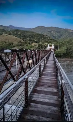 a wooden bridge over the water with mountains in the background at La Fonte di Luce in Santa Fe de Antioquia