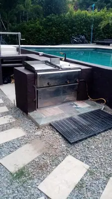 a grill sitting on the ground next to a pool at La Fonte di Luce in Santa Fe de Antioquia