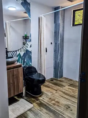 a bathroom with a black toilet and a shower at La Fonte di Luce in Santa Fe de Antioquia