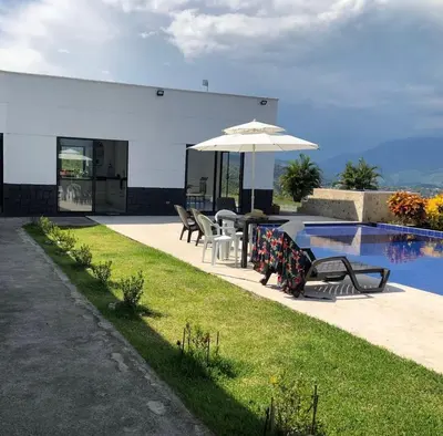 a table with an umbrella next to a swimming pool at Finca El Paraíso in Santa Fe de Antioquia