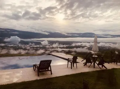a patio with chairs and a table and a pool at Finca El Paraíso in Santa Fe de Antioquia