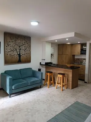 a living room with a blue couch and a kitchen at Acogedor Apartaestudio en Laureles in Medellín