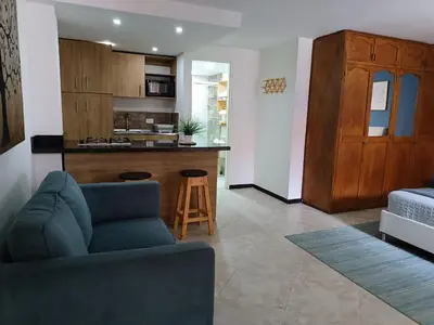 a living room with a couch and a kitchen at Acogedor Apartaestudio en Laureles in Medellín