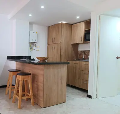 a kitchen with wooden cabinets and a counter with stools at Acogedor Apartaestudio en Laureles in Medellín