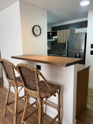 a kitchen with two chairs and a counter with a clock at Loft poblado con parqueadero in Medellín