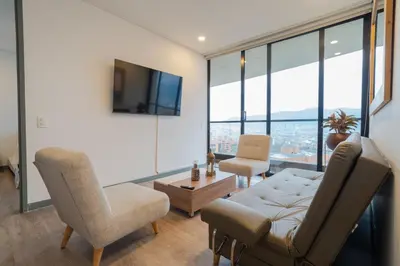 a living room with a couch and chairs and a tv at CLASS Suites in Medellín