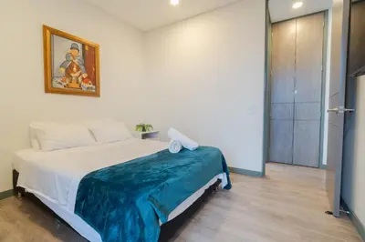 a bedroom with a bed with a blue blanket on it at CLASS Suites in Medellín