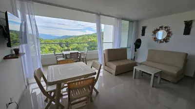 a living room with a table and chairs and a balcony at Relájate y Disfruta, Apartamento con Piscina, Tobogán y Vista Espectacular en Santa Fé de Antioquia in Santa Fe de Antioquia