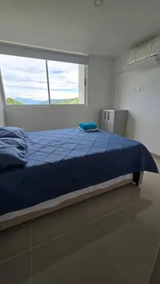 a bed in a room with a large window at Relájate y Disfruta, Apartamento con Piscina, Tobogán y Vista Espectacular en Santa Fé de Antioquia in Santa Fe de Antioquia