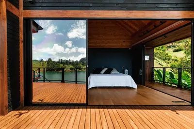 a bedroom with a bed on a deck with a large window at Sienna Casa del Lago in Guatapé