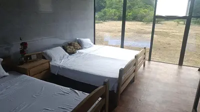 two beds in a room with a large window at family home in Honda
