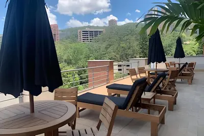 a balcony with chairs and tables and umbrellas at Exclusive apto in Poblado in Medellín