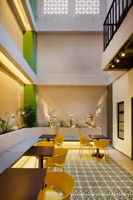 a restaurant with tables and yellow chairs and plants at Hotel Attic 33 in Medellín