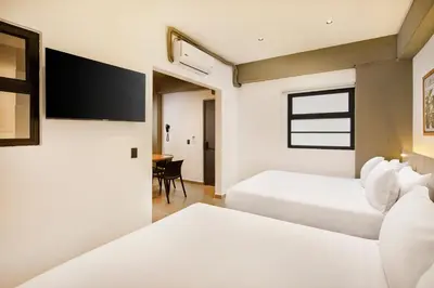 a hotel room with two beds and a flat screen tv at Hotel Attic 33 in Medellín