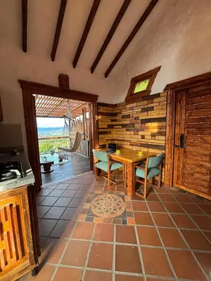 a living room with a table and chairs and a patio at Glamping Montesereno in El Peñol