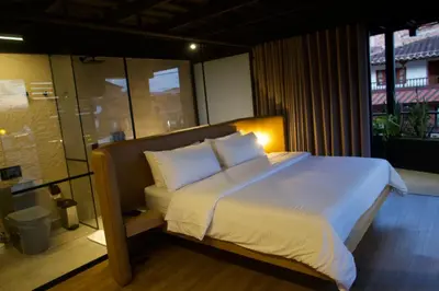 a bed with white sheets and pillows in a room at Hotel Casa Leon Rooftop in Rionegro