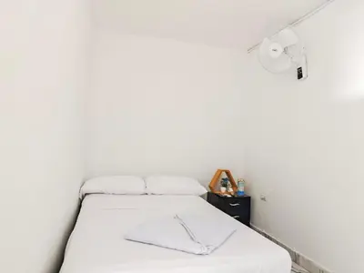 a bed in a room with a white wall at Casa Eclat in Medellín