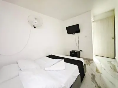 a white room with a bed and a tv at Casa Eclat in Medellín