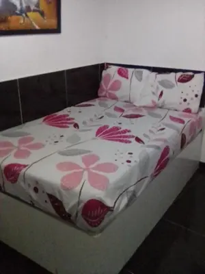 a bed with a flowered blanket on top of it at Hotel Minorista plaza in Medellín