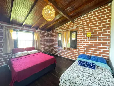 a bedroom with two beds and a brick wall at Casa Campestre Familiar in Medellín