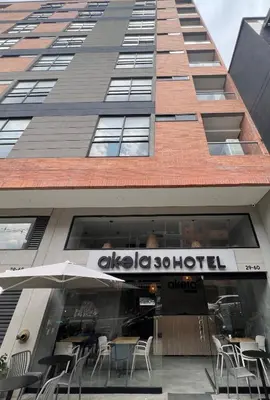 a building with tables and chairs in front of it at Akela30 Hotel in Medellín