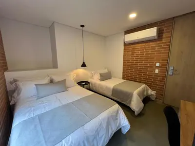 a bedroom with two beds and a brick wall at Akela30 Hotel in Medellín