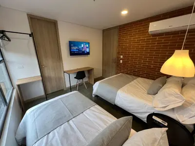 a hotel room with two beds and a tv at Akela30 Hotel in Medellín