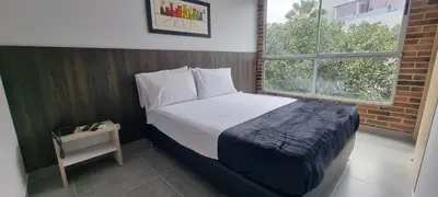 a bedroom with a bed and a night stand and a window at Laureles City Retreat, Cold AC in Medellín