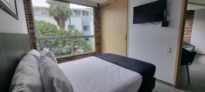 a bedroom with a bed and a large window at Laureles City Retreat, Cold AC in Medellín