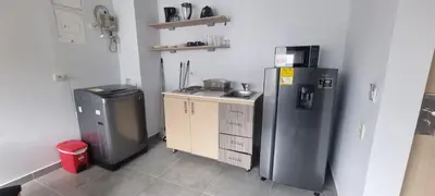 a small kitchen with a refrigerator and a trash can at Laureles City Retreat, Cold AC in Medellín