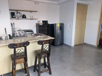 a kitchen with two bar stools and a refrigerator at La 70, Laureles Condo, Cold AC in Medellín