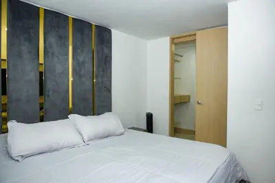 a bedroom with a white bed and a wooden door at Luxurious apartment in Las Palmas in Medellín