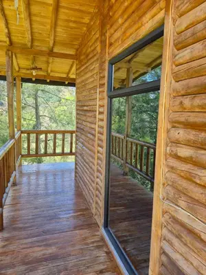 a porch of a log cabin with a large glass door at Cabaña con Jacuzzi cerca al Peñol in Chiquinquirá