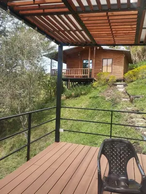 a chair on a deck with a house in the background at Cabaña con Jacuzzi cerca al Peñol in Chiquinquirá