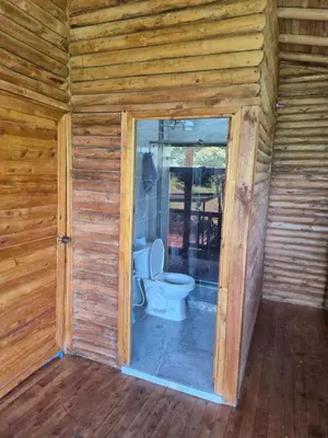 a bathroom with a toilet in a wooden cabin at Cabaña con Jacuzzi cerca al Peñol in Chiquinquirá