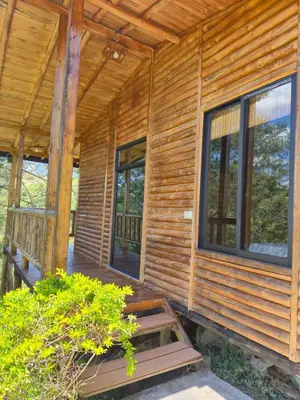 a log cabin with a porch and windows at Cabaña con Jacuzzi cerca al Peñol in Chiquinquirá