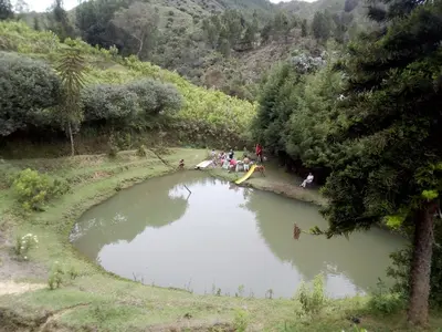 a group of people sitting around a small pond at Las Jodelinas in Guarne
