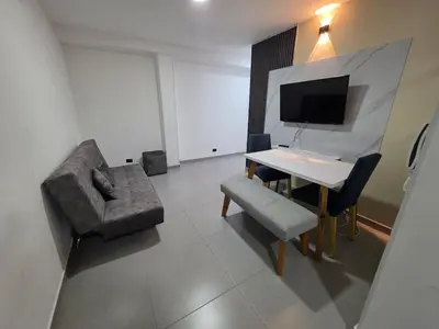 a room with a table and a chair and a television at Elegant apartment Laureles Estadio in Medellín