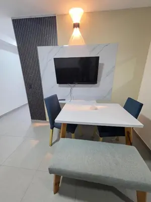 a white table and chairs with a tv on a wall at Elegant apartment Laureles Estadio in Medellín