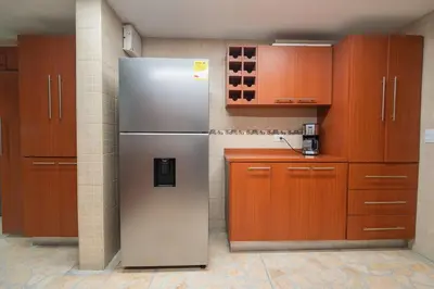 a kitchen with a stainless steel refrigerator and wooden cabinets at Lux Lleras l Daily Cleaning l AC l Visitrs Allowed in Medellín