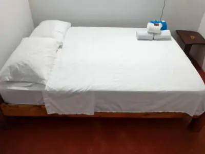 a bedroom with a bed with white sheets at Casa de descansó la pradera