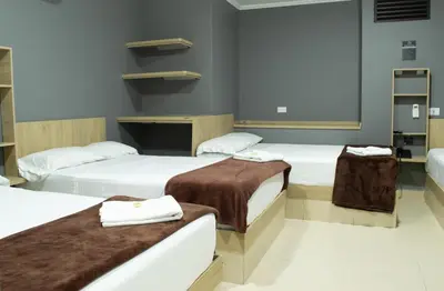 a room with three beds with towels on them at Hotel Ruiseñor Itagui in Itagüí