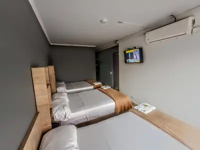 a small room with two beds and a tv at Hotel Ruiseñor Itagui in Itagüí