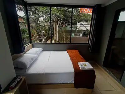 a bed in a room with a large window at Hotel Ruiseñor Itagui in Itagüí